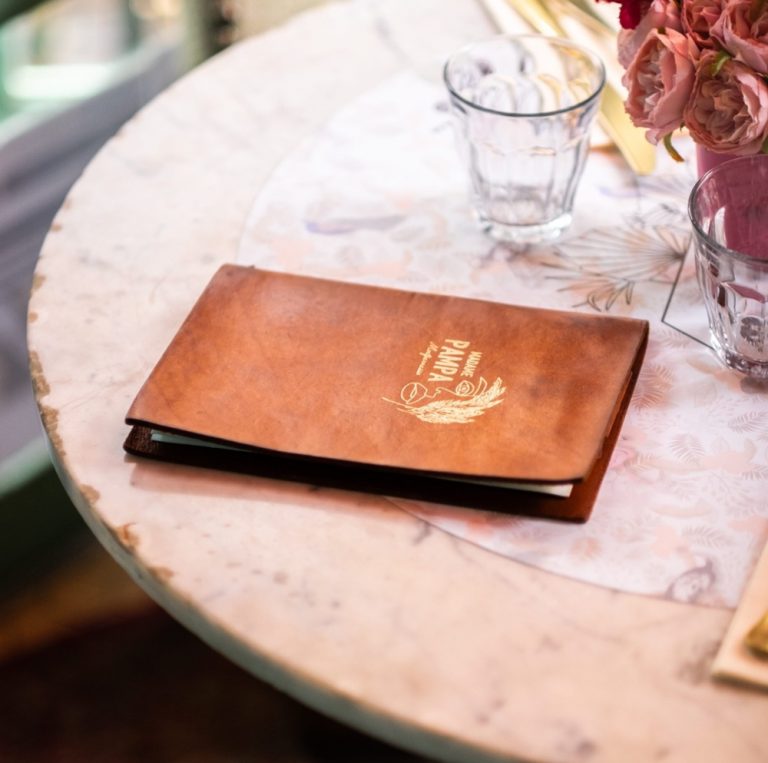 Porte menu en cuir marron personnalisé d'un marquage doré sur une table